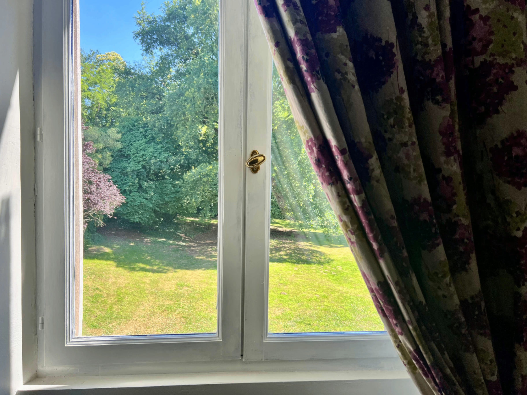 La Chambre Palerme — garden view through tall windows and floral curtains